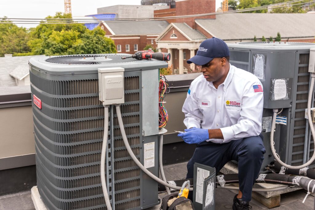 HVAC technician works on air conditioning unit. 